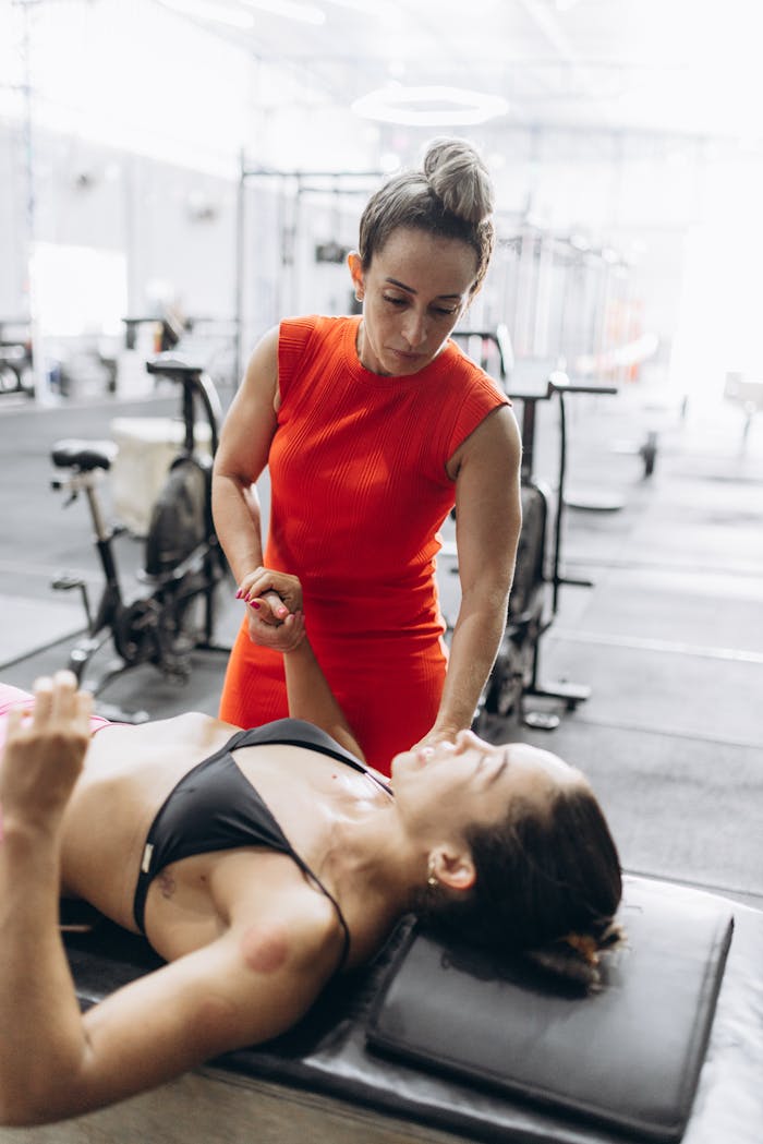 A therapist assists a woman during a rehabilitation session in a gym.
