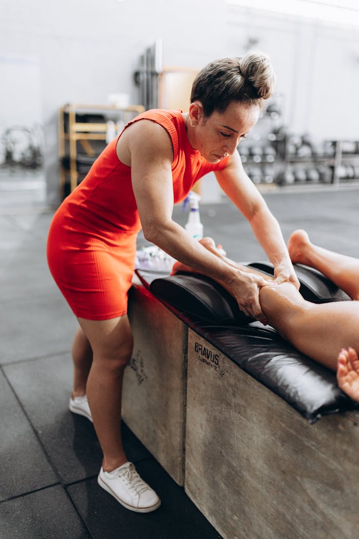 A professional giving a leg massage in a gym environment, focusing on recovery and therapy.